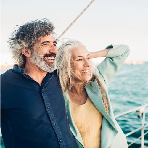 Man and woman on a boat with wind in their hair, representing The Boat Galley's All-Access Pass for living on a boat and cruising courses.