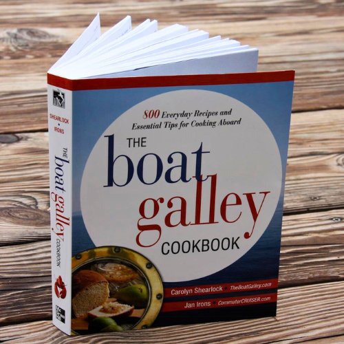 The Boat Galley Cookbook on a dock, celebrating its publication and connection to boat life.