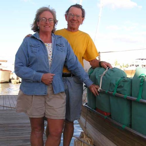 Carolyn and Dave Shearlock standing next to their first cruising boat, Que Tal, marking the start of their liveaboard cruising journey in 2002.