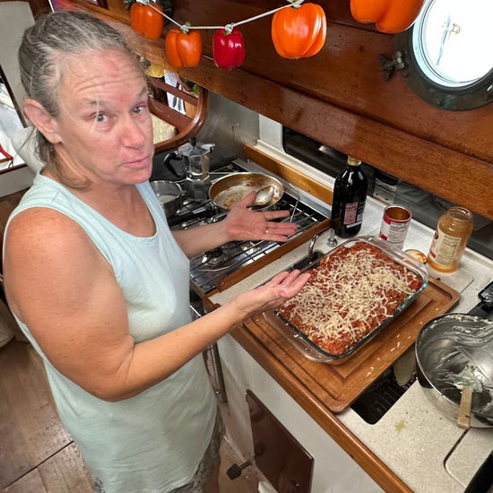 Picture of Nica Waters, creator of Provisioning, Meal Planning, and Food Storage course making lasagna in the galley of her 28' sailboat