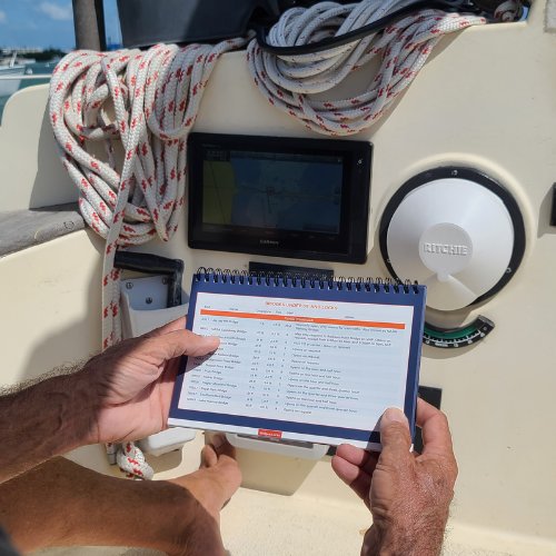 Man using a cruising guide in the cockpit of a boat, planning routes and stops for a smooth voyage