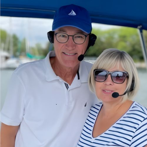 Two people wearing 2Talk headsets on a boat with a scenic background